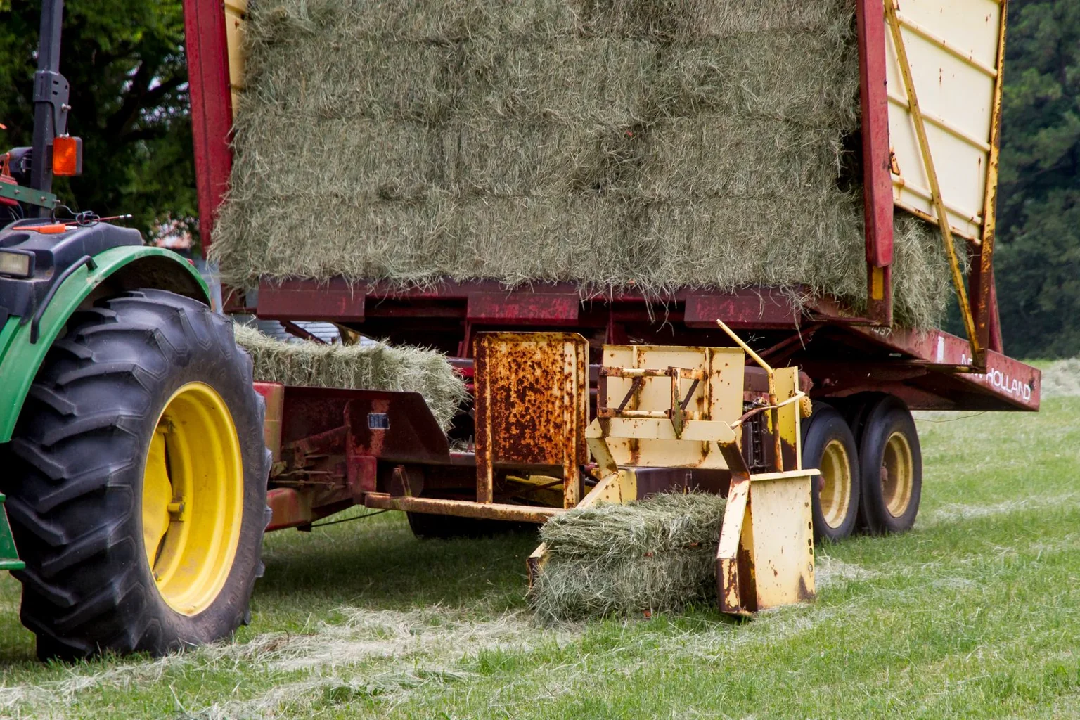 A square baler producing hay bales in a field